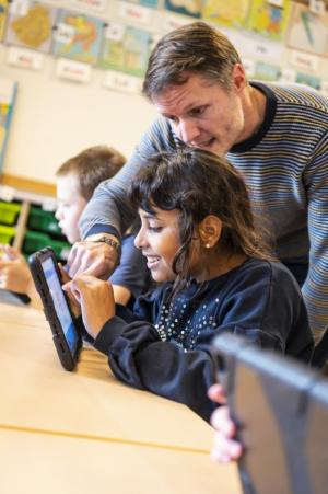 Stedelijk buitengewoon onderwijs_leerkracht helpt lachend meisje op de iPad  in De Leerexpert Burchtse Weel