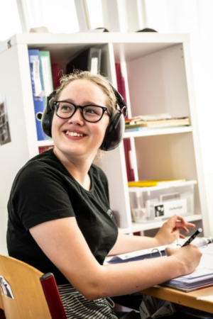 Stedelijk buitengewoon onderwijs_meisje met bril en oorbeschermers lacht inDe Leerexpert Jozef Van Poppelstraat